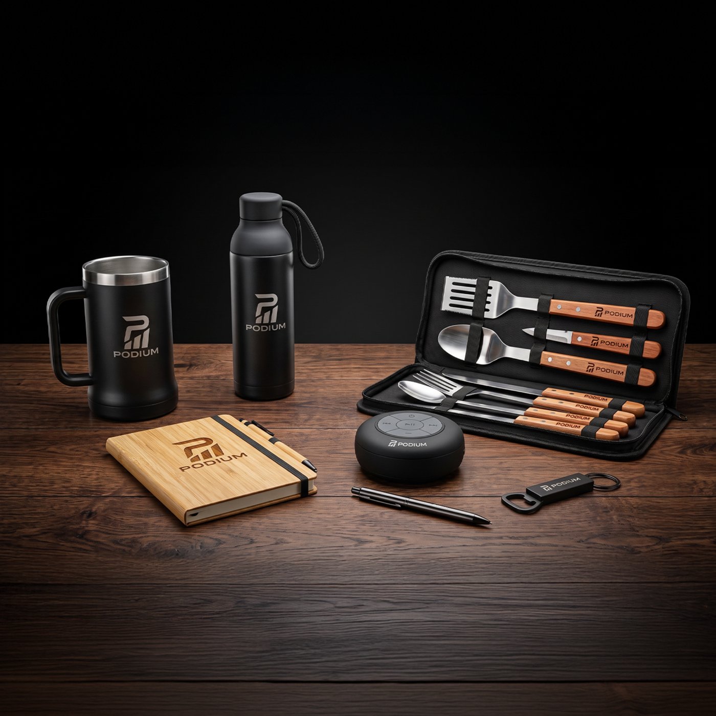 Brindes corporativos personalizados da Podium: caneca, garrafa, caderno de bambu, kit churrasco, caixa de som, caneta e chaveiro sobre mesa de madeira